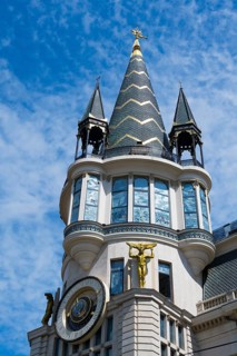 Close-up of a tower with a golden statue and ornate architectural details, astronomical clock,