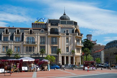 Market with stalls and people in front of a historic building with decorative roof, Royal Casino