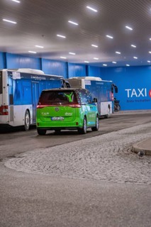 Interior view of a bus stop with green shuttle and buses, urban atmosphere, Deer E-Mobility Shuttle