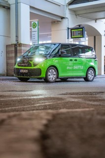 Green shuttle at a covered stop, quiet urban area, Deer E-Mobility Shuttle Service, Calw, Germany