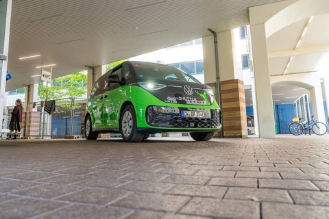Green VW under roof in urban environment, Deer E-Mobility Shuttle Service, Calw, Germany