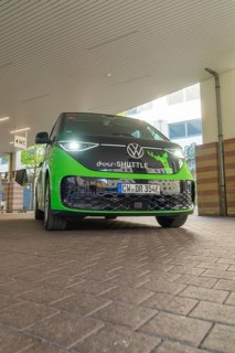 Green VW from the front in an urban, modern environment, Deer E-Mobility Shuttle Service, Calw,