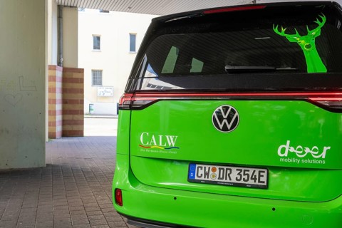 Volkswagen in green with lettering on the back in an urban environment, Deer E-Mobility Shuttle
