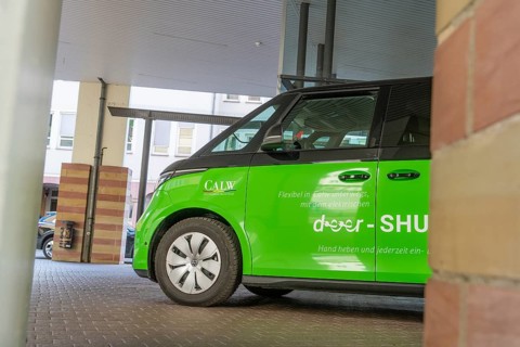 Green car in a parking lot, modern and stylish under canopy, Deer E-Mobility Shuttle Service, Calw,