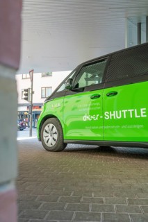 Green shuttle is under roof in urban area, Deer E-Mobility Shuttle Service, Calw, Germany