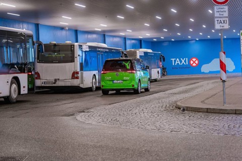 Bus station with green shuttle and taxi signs, urban scene at night, Deer E-Mobility Shuttle