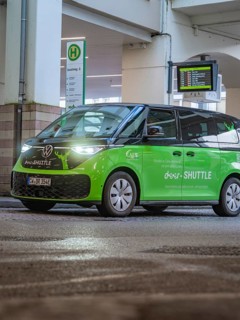 Green shuttle at a bus stop, equipped with digital display and urban design, Deer E-Mobility