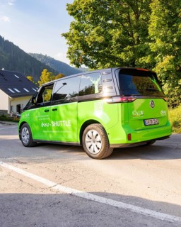 Green car on road in picturesque landscape with mountains in the background, Deer E-Mobility
