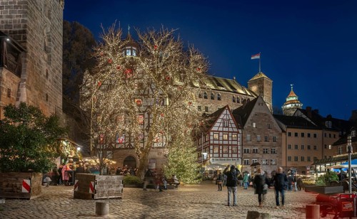 Christmassy illuminated square with the historic Pilate House with advent calendar, in the evening