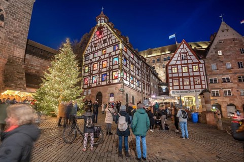 Christmassy illuminated square with the historic Pilate House with advent calendar, in the evening