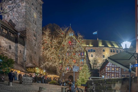 Christmassy illuminated square with the historic Pilate House with advent calendar, in the evening