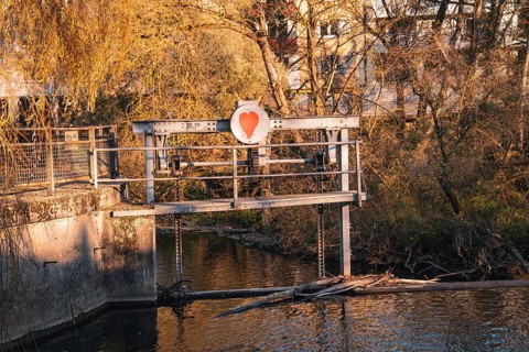 Dam with heart symbol in front of an autumnal riverbank, Stadtgarten Pforzheim, Germany