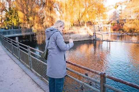 Woman photographing a river on an autumn day, Stadtgarten Pforzheim, Germany