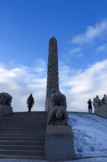 Monolith and sculptures on snowy stairs. People standing and admiring, Vigeland Sculpture Park Oslo