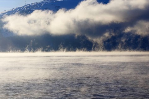 Clouds of fog over a lake with mountain scenery and clouds Norway