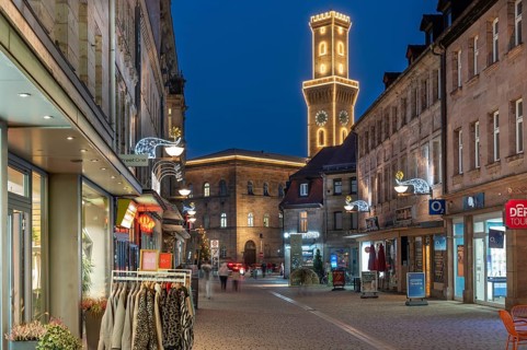 Pedestrian zone in evening lighting, the illuminated town hall tower at the back, blue evening sky,