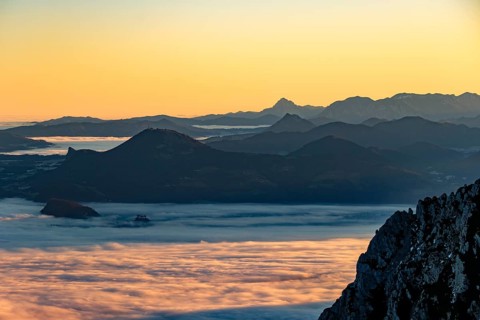 Sunrise in the mountains, view of Salzburg with fog, silhouette of mountain ranges in the back,