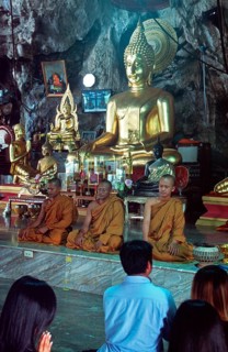 Buddha statue, monks and believers praying, Wat Tam Sua monastery near Krabi, Thailand, December