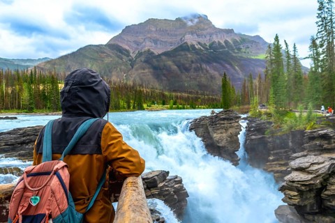 Backpacker enjoying the breathtaking view of athabasca falls cascading through the rugged landscape