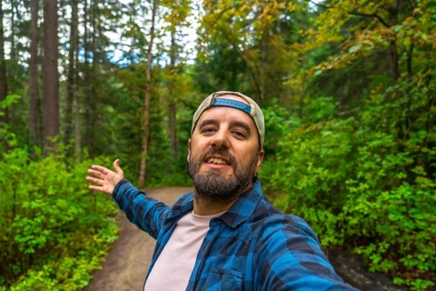 Happy hiker taking a selfie with open arms while walking the overlander falls trail in mount robson