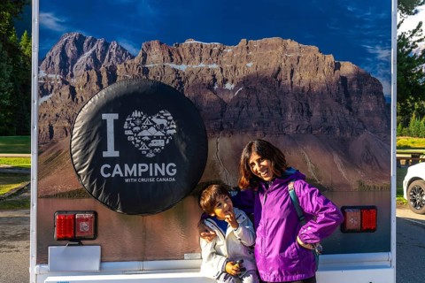 Mother and son posing happily in front of their rv, featuring a large i love camping graphic and a