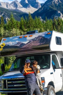 Father and son showing thumbs up, enjoying their rv trip in the majestic canadian rockies near