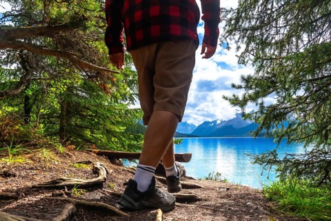 Hiker walking along a forest path toward maligne lake's turquoise waters, framed by a mountain