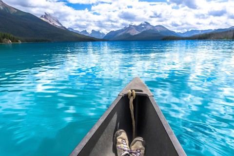 Hiking boots inside a canoe navigating the turquoise waters of maligne lake with its surrounding