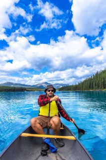 Tourist paddling a canoe in maligne lake under a beautiful cloudy sky, enjoying the turquoise water