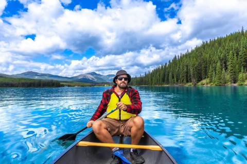 Tourist paddling a canoe on turquoise maligne lake with spirit island in the distance, enjoying the
