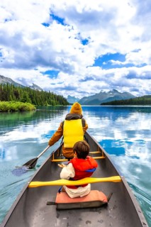 Tourists wearing life jackets are paddling a canoe on beautiful maligne lake in jasper national