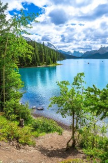 Canoes are paddling on a beautiful turquoise lake surrounded by lush green trees and mountains in