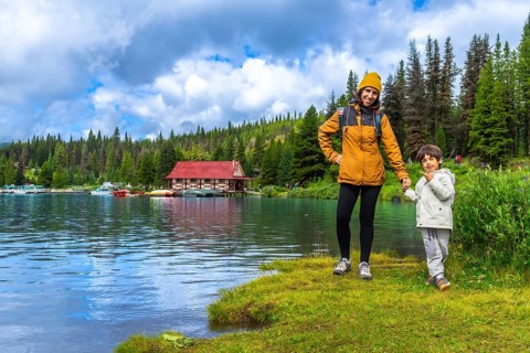 Mother and son holding hands, enjoying a scenic view of maligne lake boathouse in jasper national