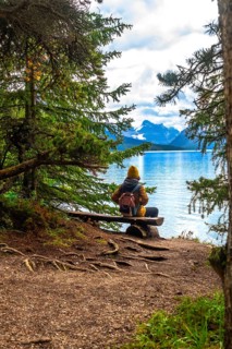 Hiker sitting on a wooden bench, admiring the breathtaking view of maligne lake and the surrounding
