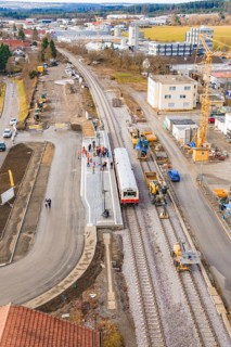 A construction site at a train station with construction work, cranes and a train. Residential