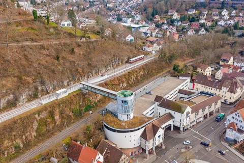 A city view with a train on the rails, surrounded by various buildings and a valley, historical