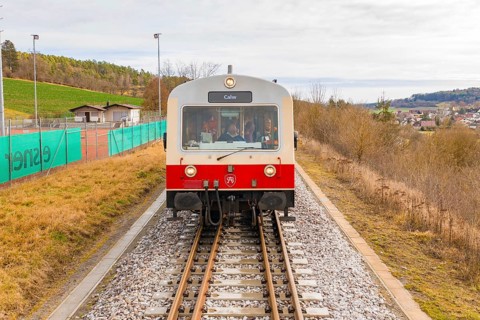 Front view of a train on the rails with landscape in the background, inscription 'Calw', historical