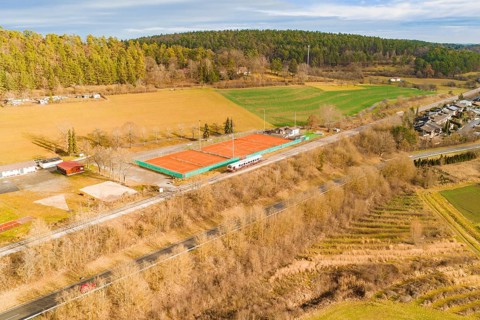 View of tennis courts next to a train line in rural surroundings, historic event, first test run