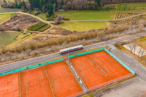 Aerial view of tennis courts next to a train line, historic event, first test run with a passenger