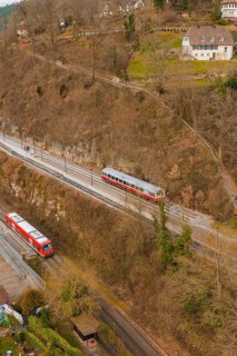 Train on tracks next to wooded hills with buildings in a wintry landscape, historic event, first