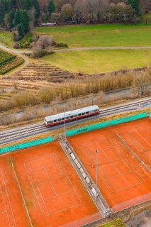 Landscape view with train next to tennis courts and meadows, historic event, first test run with
