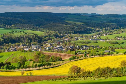 View from Schwartenberg over fields, forests, blooming rapeseed and the community of Neuhausen,