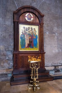 A wooden altar with icons of saints and glowing candles in a church, Svetitskhoveli Cathedral,