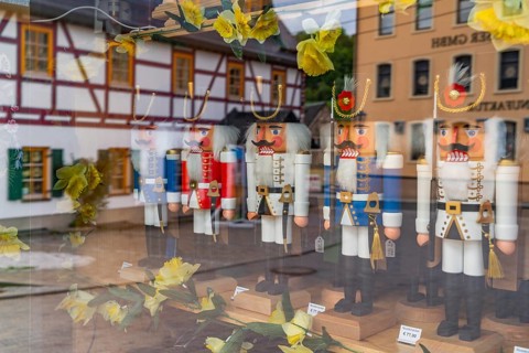 Window of a wooden nutcracker shop, reflecting a half-timbered house, health resort and toy village