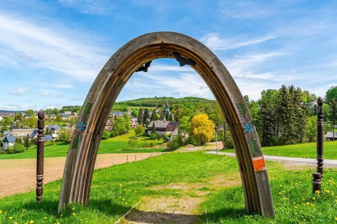 View through a wooden arch of residential buildings and landmarks of the historic mountain church,