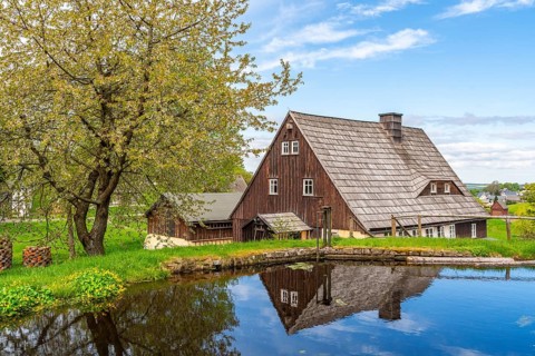 Historic houses with half-timbered timber and shingles on a pond under trees in the Seiffen