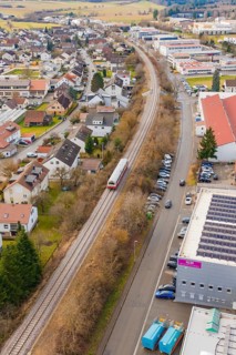 Suburb with a train, surrounded by roads, parked cars and residential buildings in a slightly