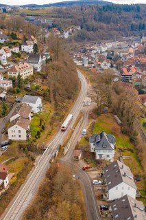 Train through suburban area with nearby houses and a wooded landscape, historic event, first test