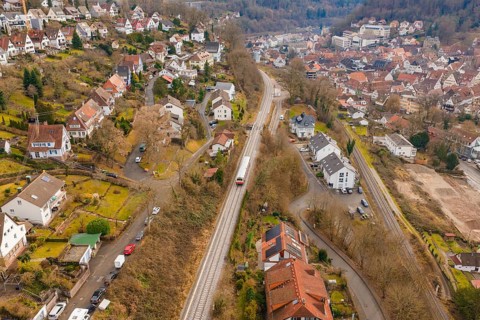 City with close-standing houses along a railway line through hilly, wooded landscape, historic
