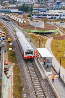 People standing on a platform next to a stopping train in an urban environment, historic event,